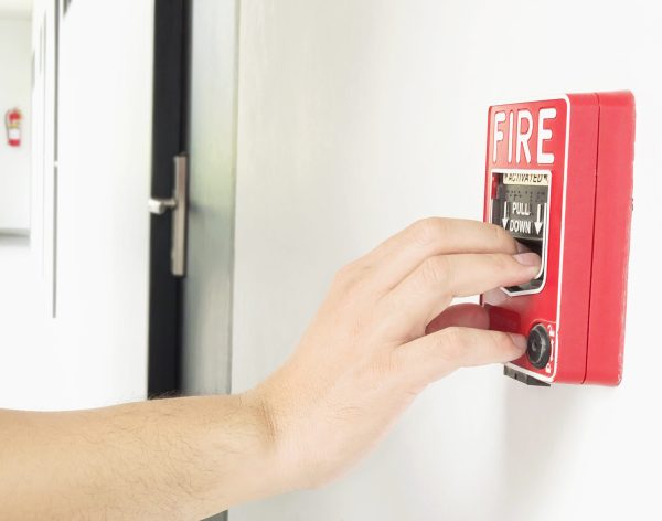Man is reaching his hand to push fire alarm hand station