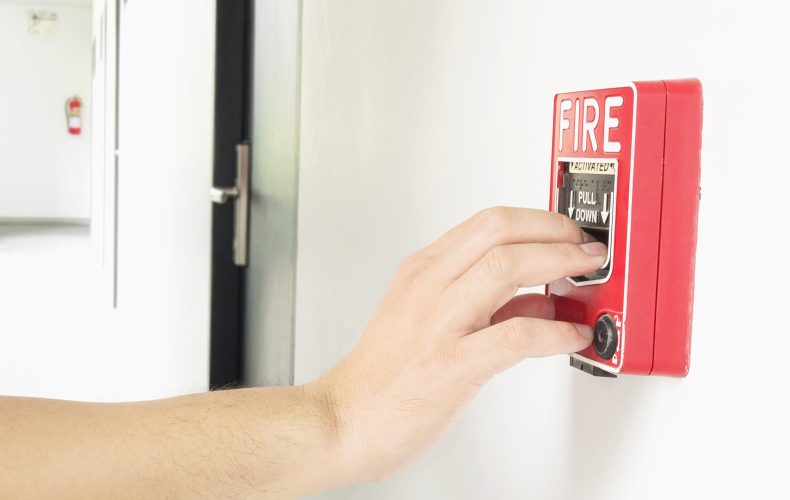 Man is reaching his hand to push fire alarm hand station