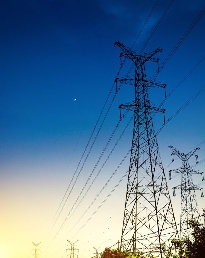 Sun setting behind the silhouette of electricity pylons