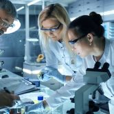 Team of Medical Research Scientists Work on a New Generation Dis Team of Medical Research Scientists Work on a New Generation Disease Cure. They use Microscope, Test Tubes, Data Implementing Technology. Laboratory Looks Busy, Bright and Modern.